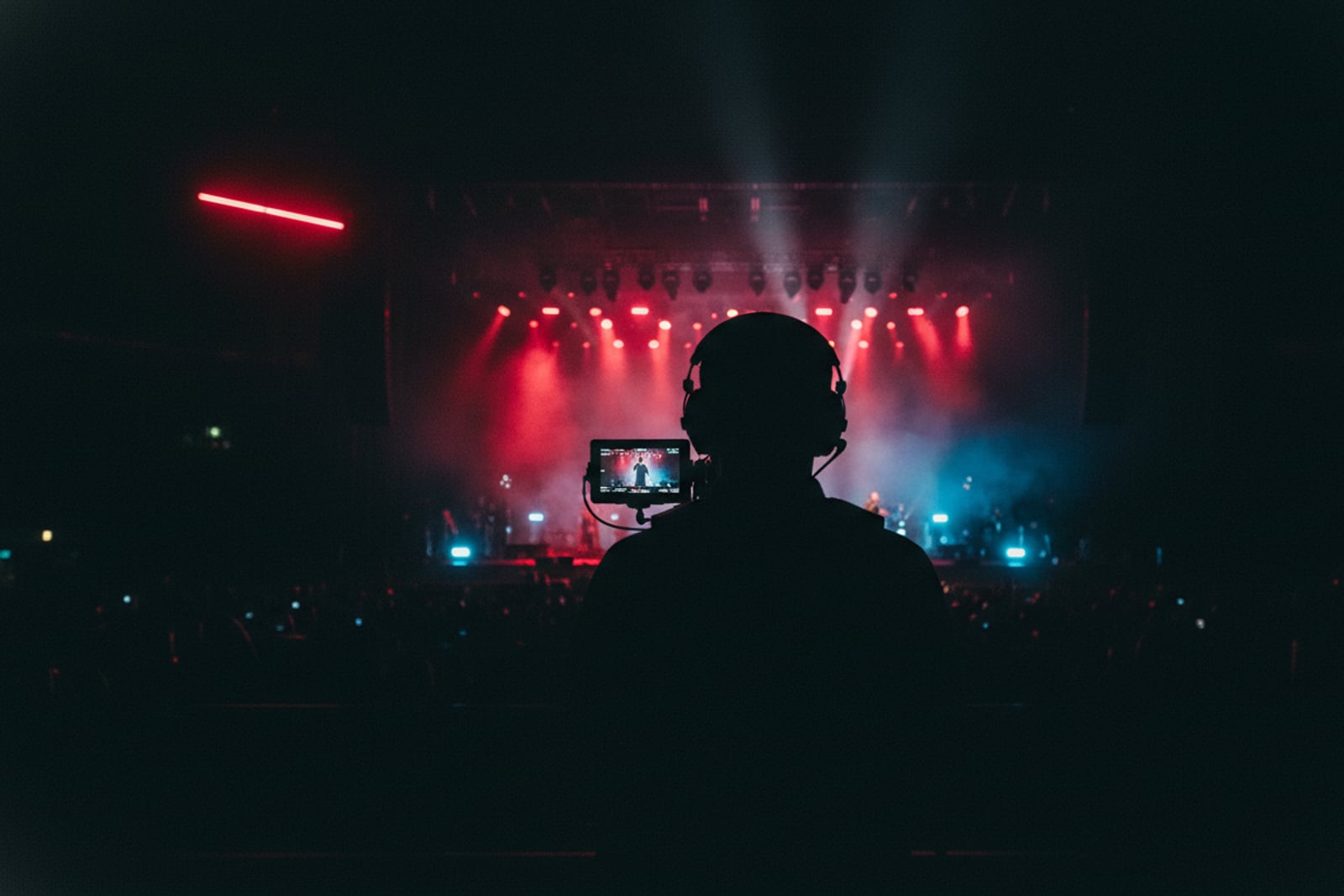 A camera operator filming a red-lit stage