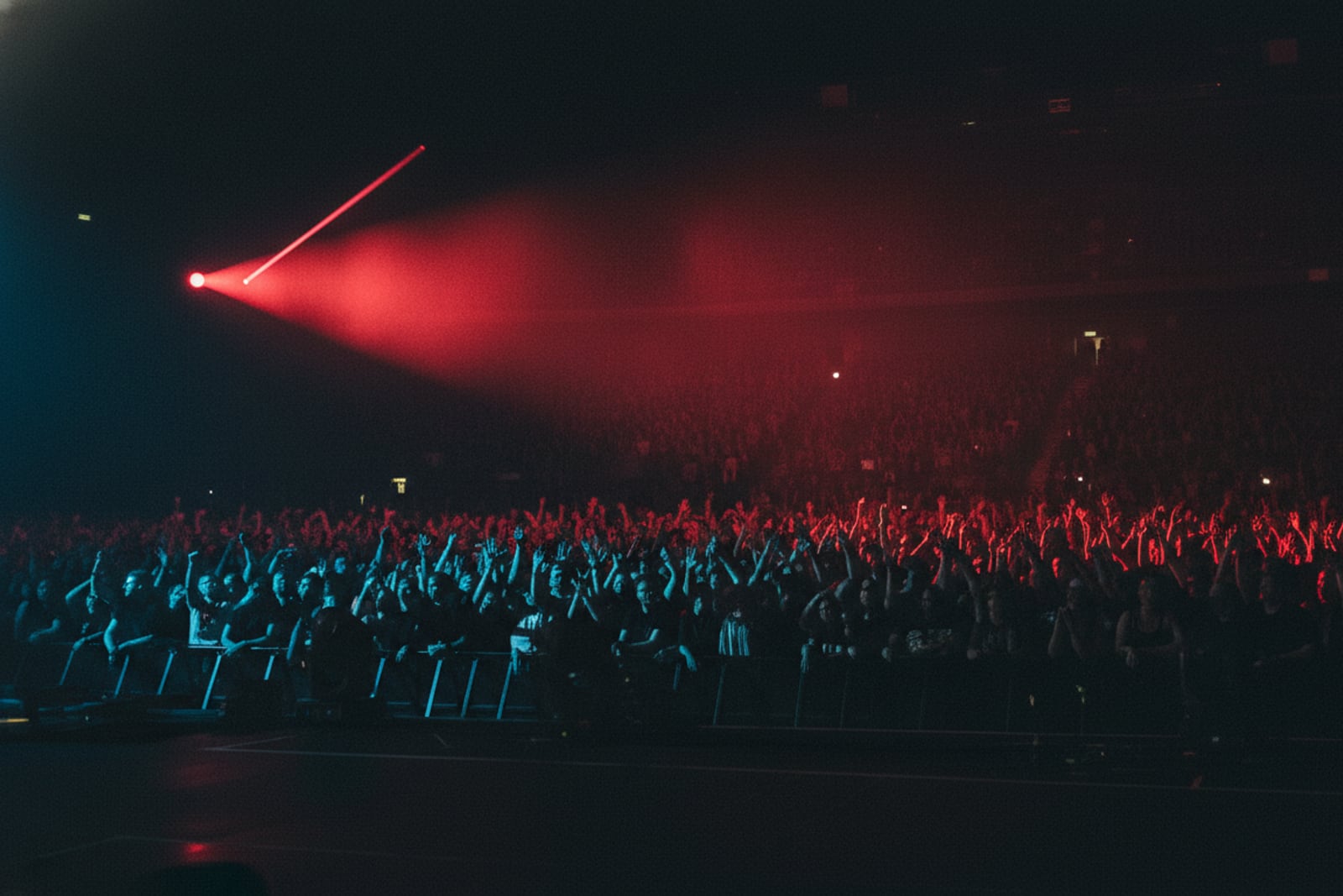A packed crowd from the stage under red and blue light